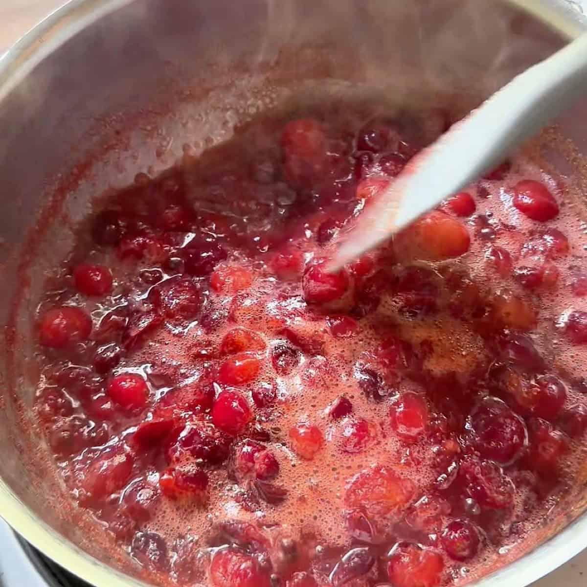Stirring the cranberry compote base in a saucepan.