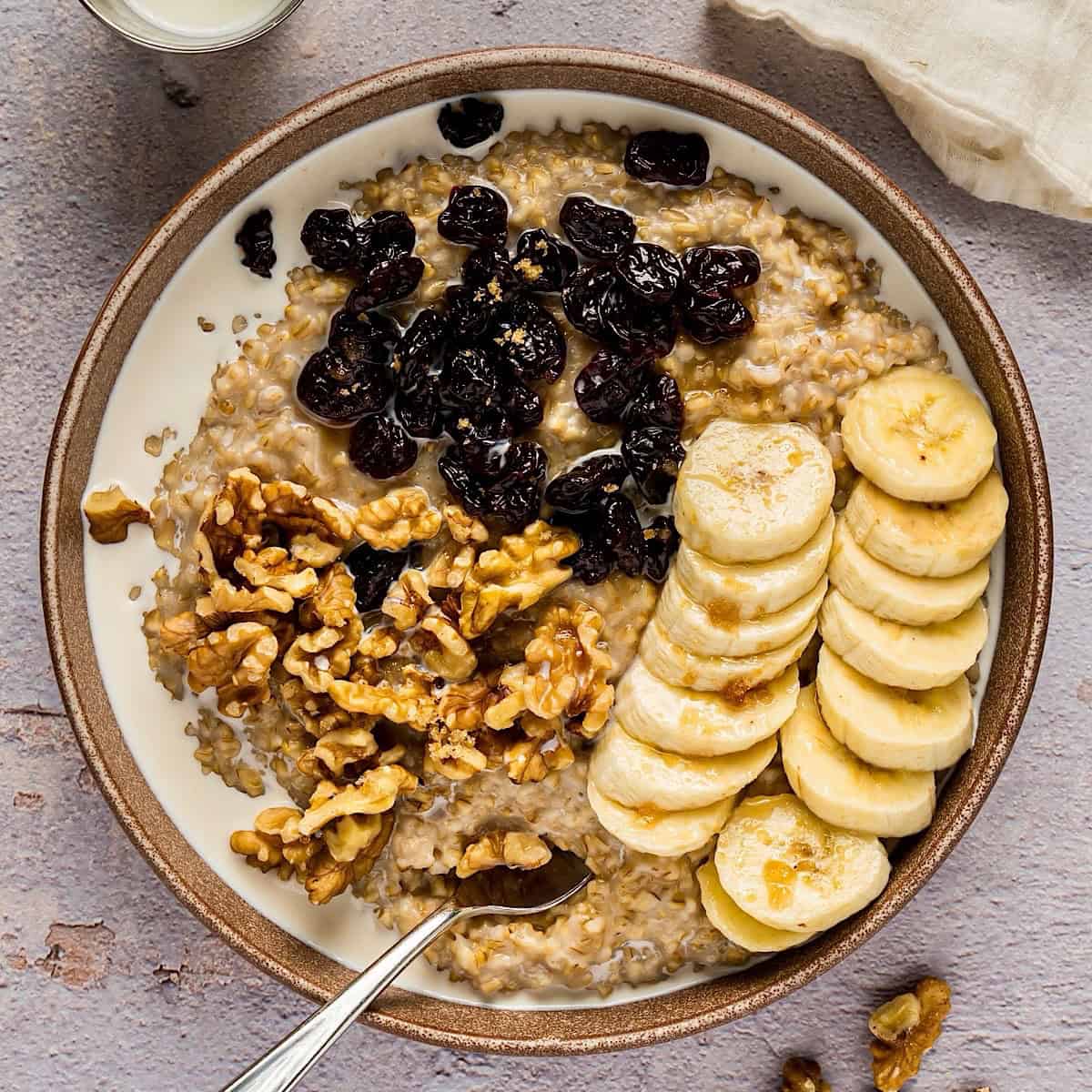Creamy Instant Pot steel cut oats in bowl with toppings and linen nearby.