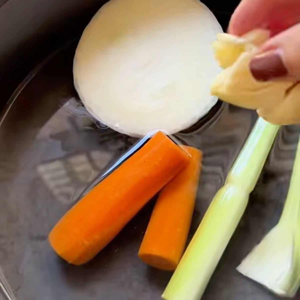 Simmering the broth with vegetables, garlic, and chicken base.