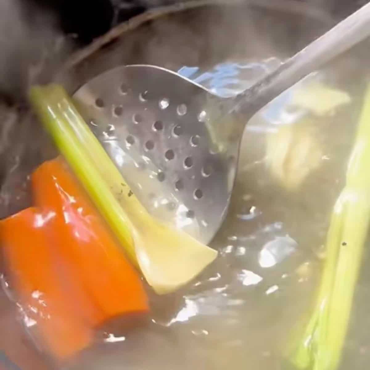 Removing vegetables with a slotted spoon.