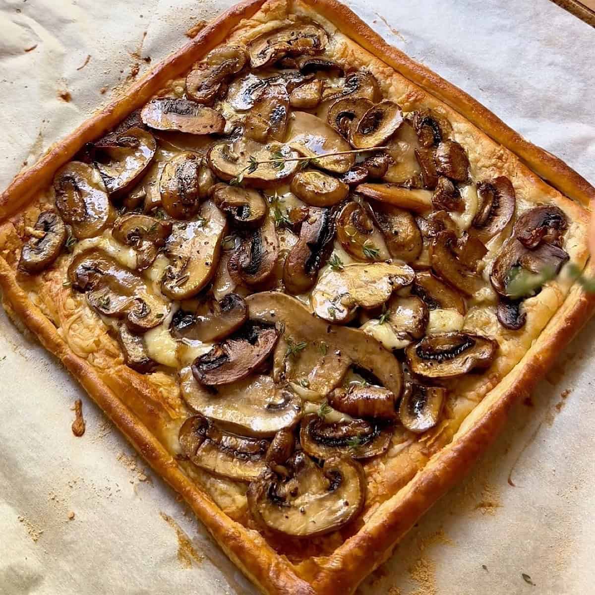 Mushroom puff pastry tart with gruyere and thyme ready to serve.