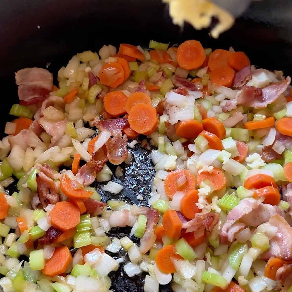 Adding mire poix and garlic to bacon grease.