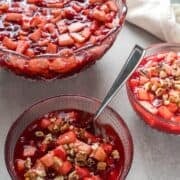 Raspberry cranberry jello salad in three decorative glass bowls with a linen.