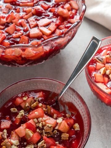 Raspberry cranberry jello salad in three decorative glass bowls with a linen.