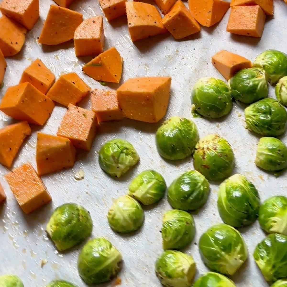 An extra large sheet pan with sweet potatoes and brussels separated.