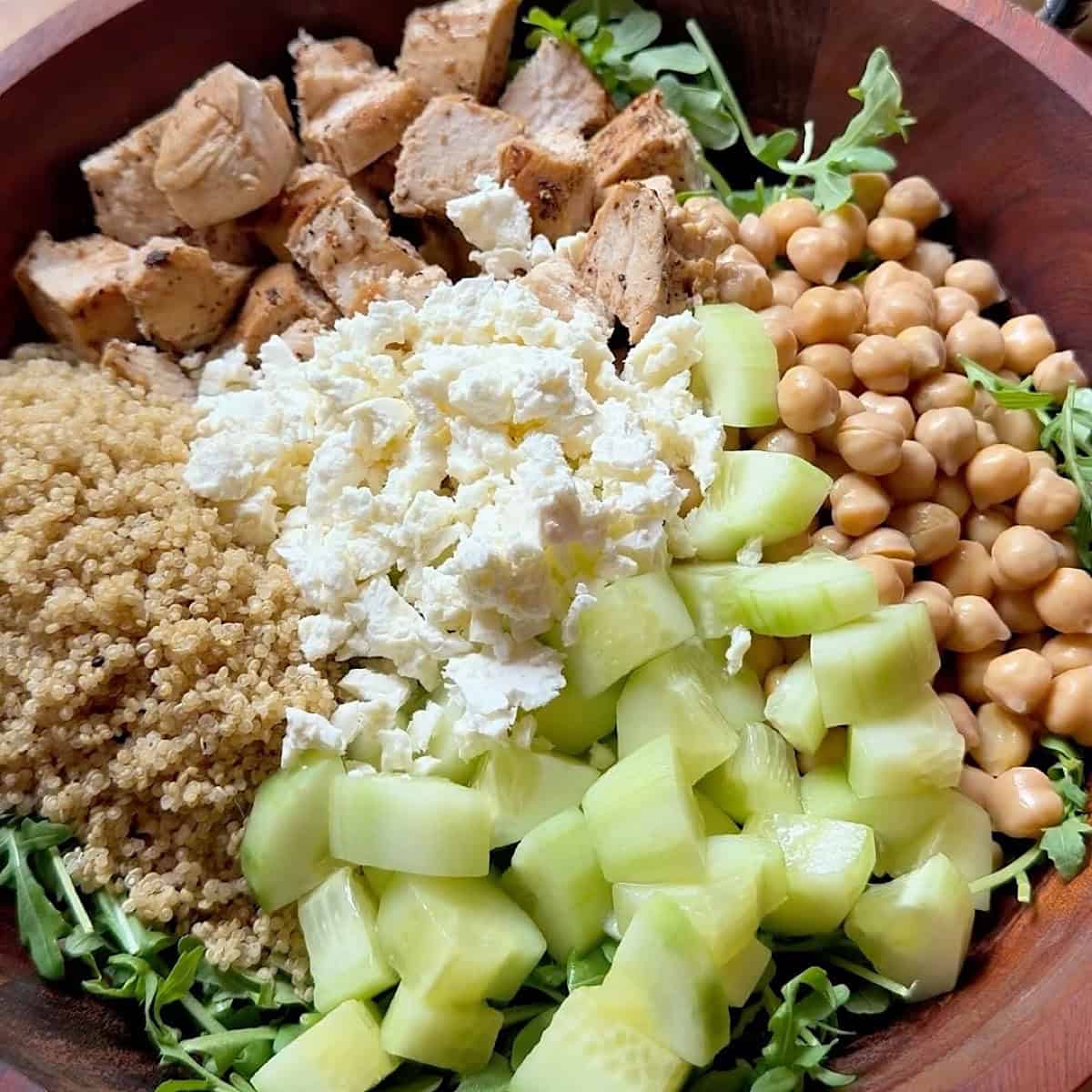 Adding chicken, and other ingredients to the arugula lettuce base.