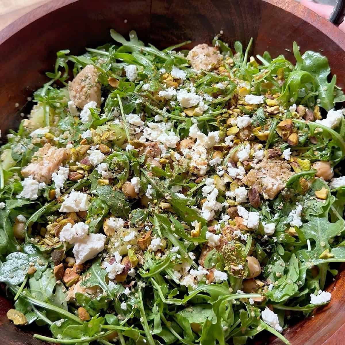 Tossed chicken arugula salad with topped with crushed pistachios and extra feta cheese.