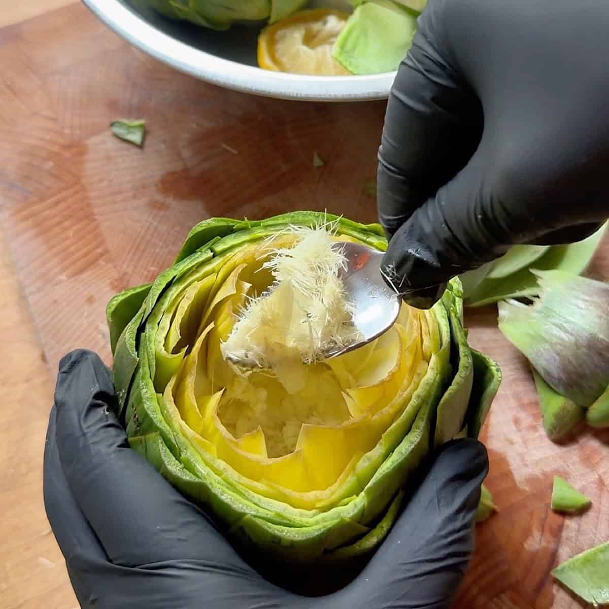 Removing the fuzzy part of the artichoke with a spoon.