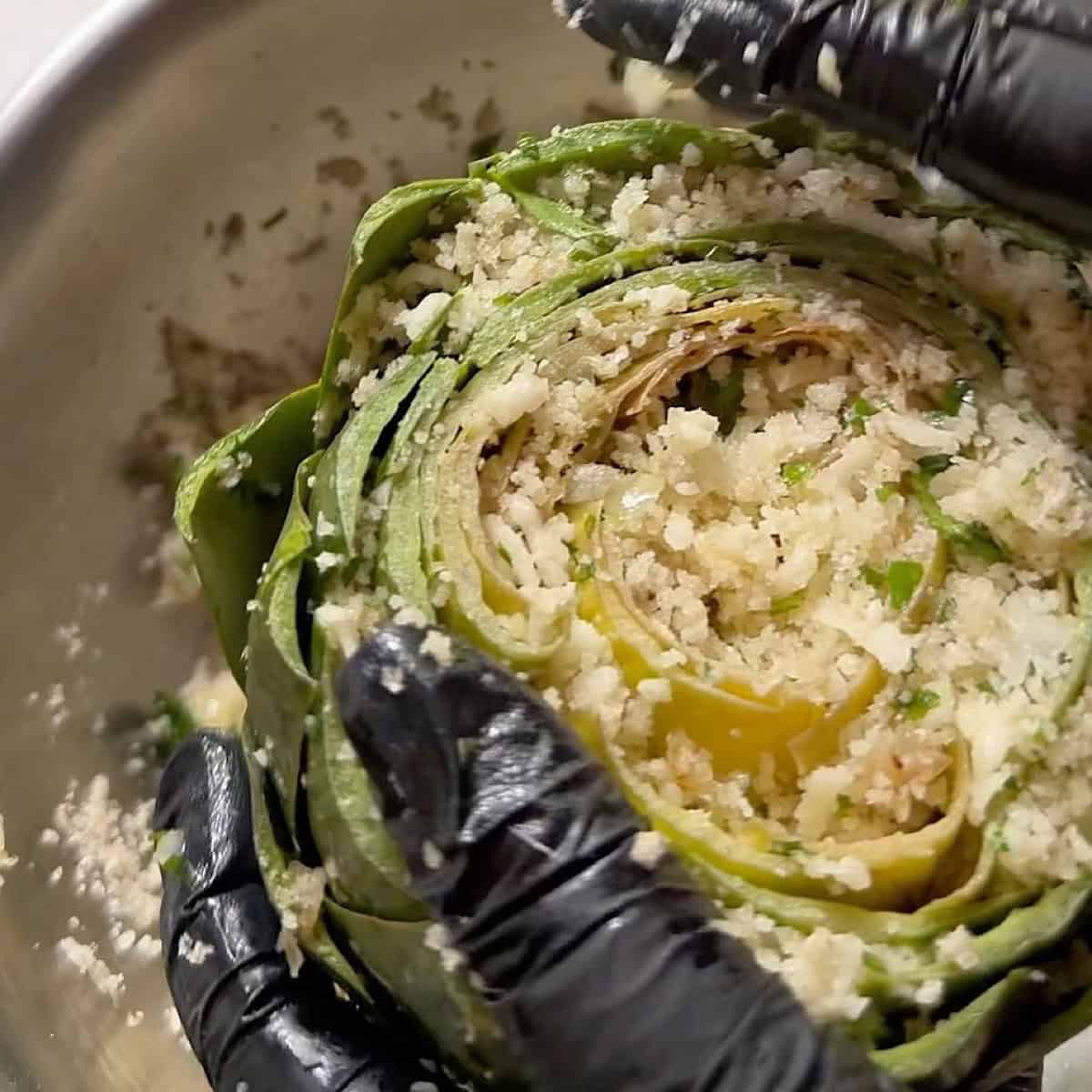 Stuffing the artichoke with panko breadcrumb filling.
