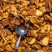 Oven baked Christmas Chex mix with Cheez-Its and a decorative scoop for serving.