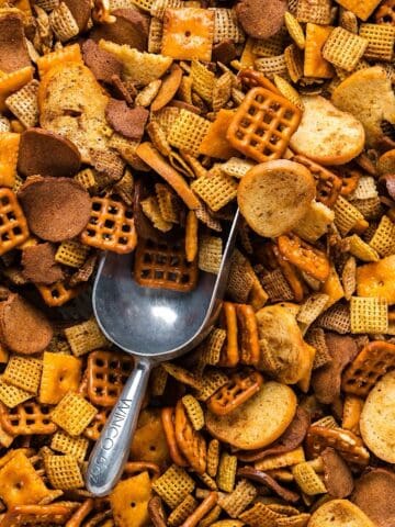 Oven baked Christmas Chex mix with Cheez-Its and a decorative scoop for serving.