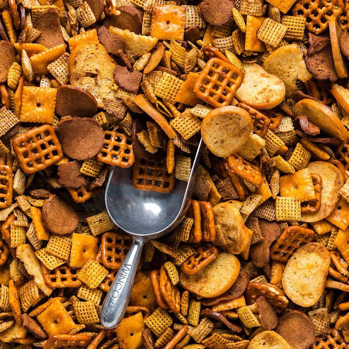 Oven baked Christmas Chex mix with an aluminum scoop for serving.