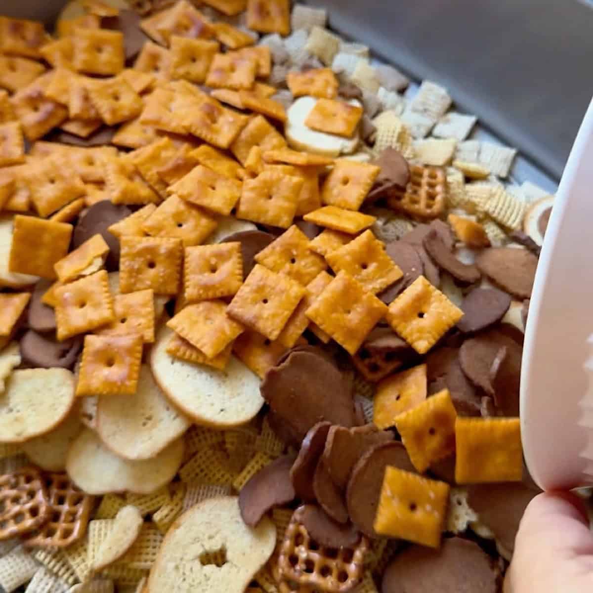 Combining the Chex Mix with pretzels and other dry ingredients.