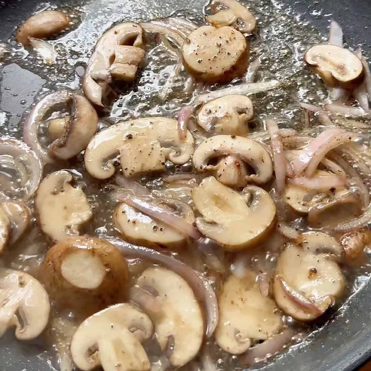 Mushrooms and onions sauteeing in bacon grease.
