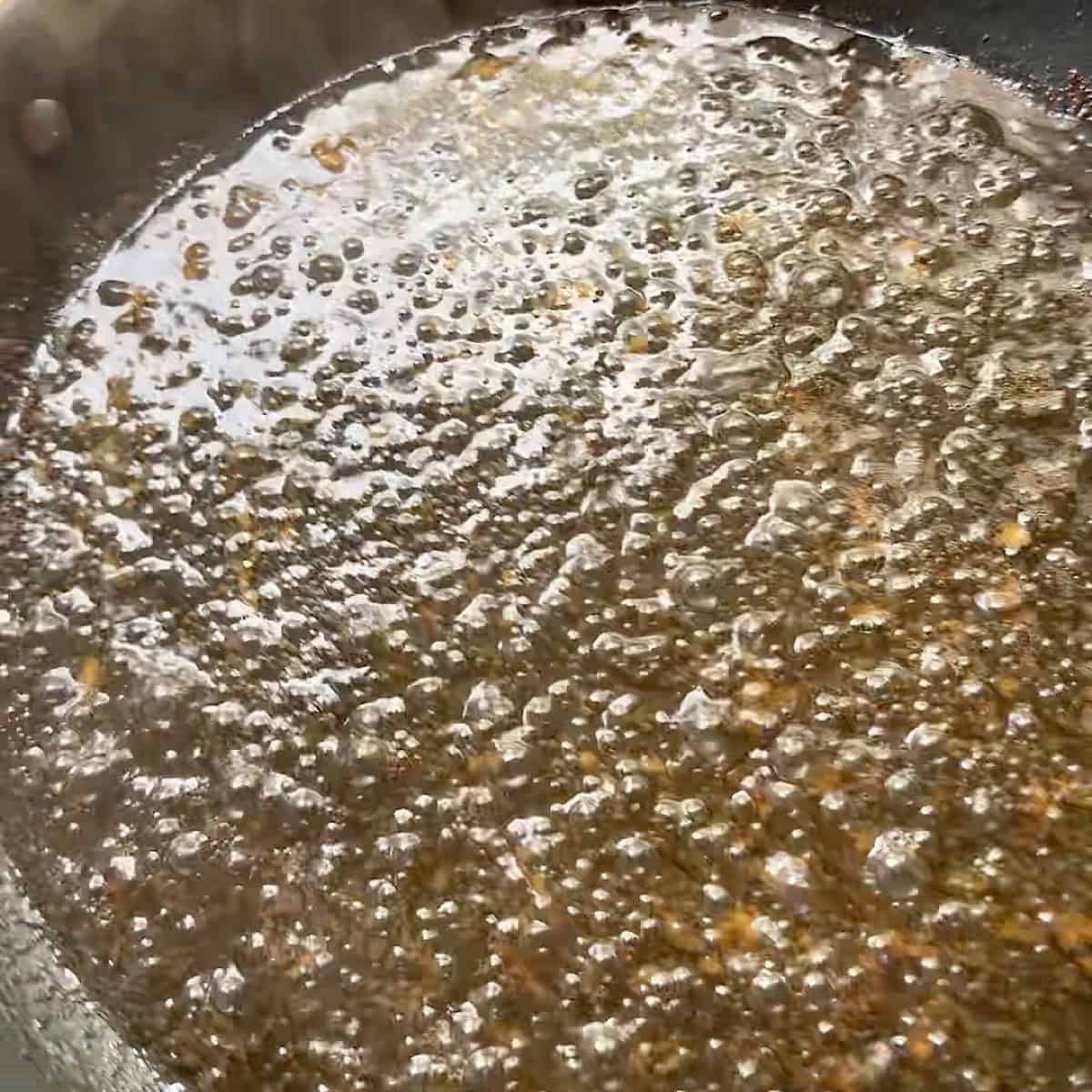 Warm bacon dressing bubbling in skillet.