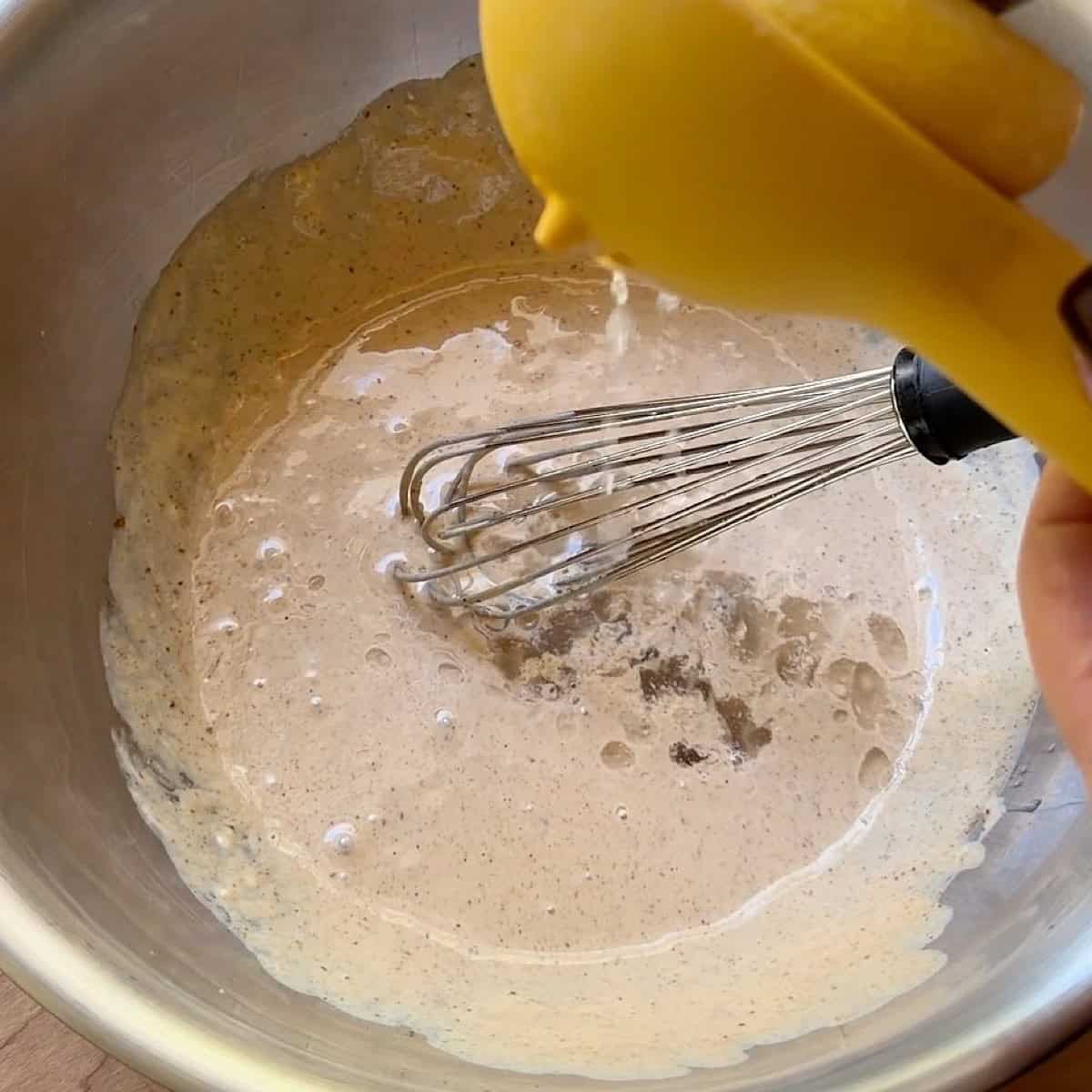 Adding lemon juice to the whisked base.