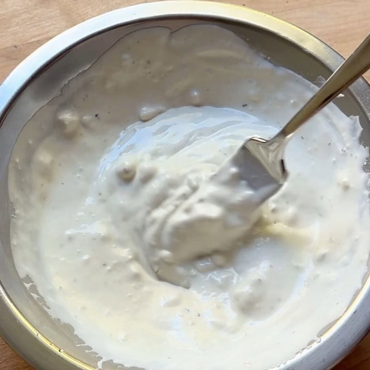 Whisked homemade buttermilk blue cheese dressing in a bowl.