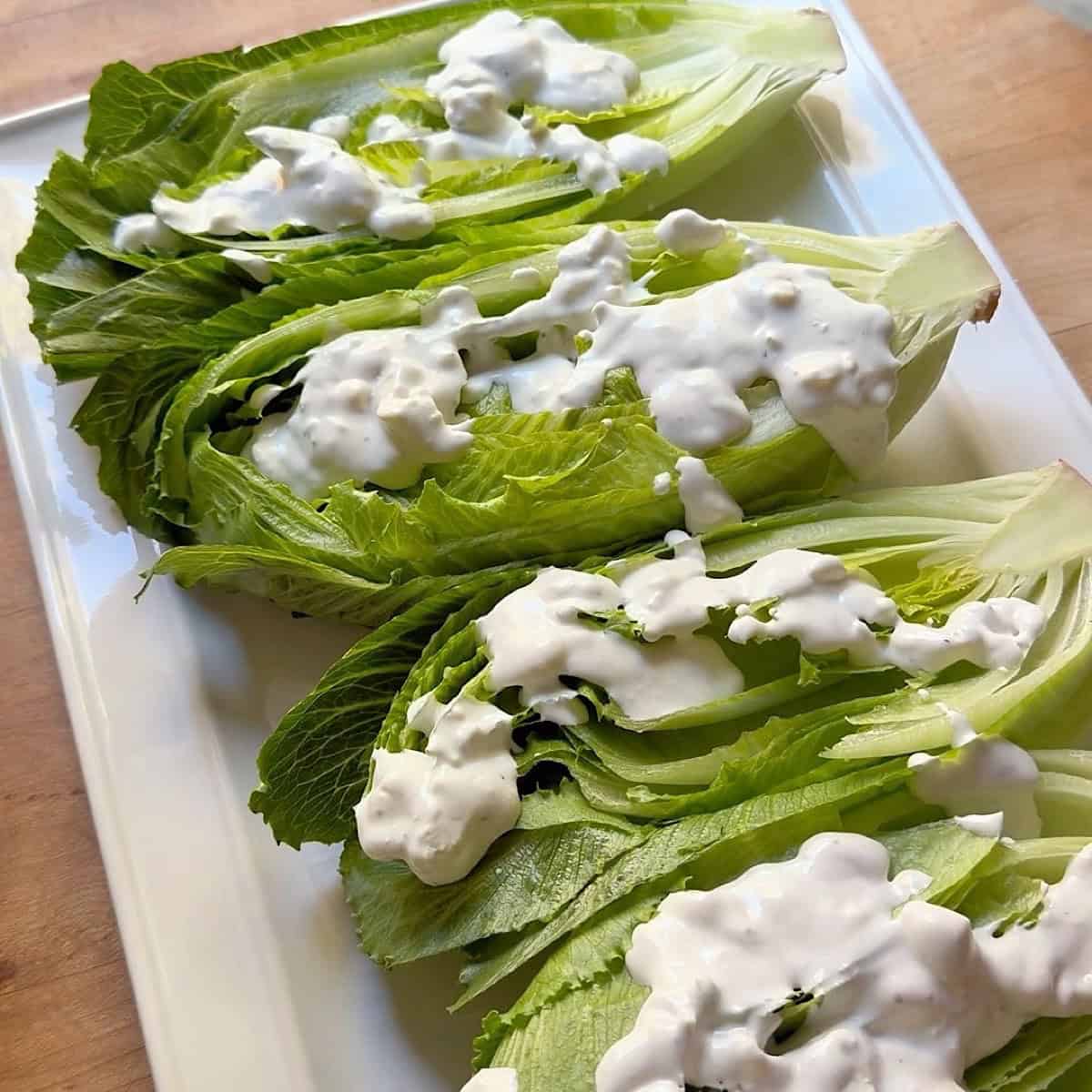 Romaine wedges with dressing layered on top.