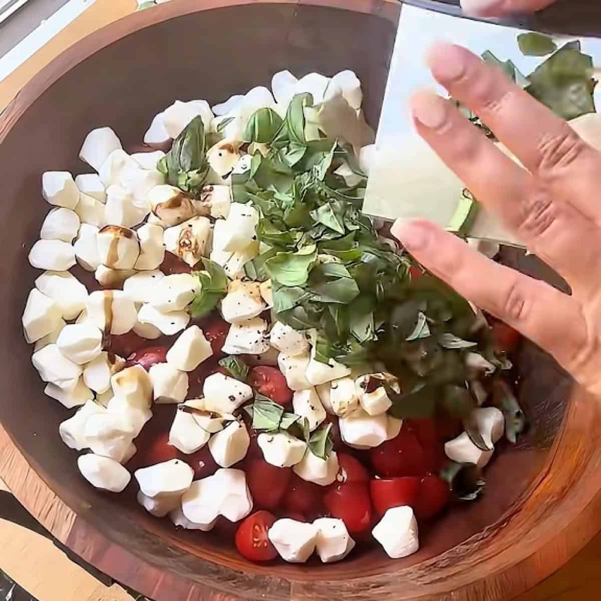 Adding chopped basil to the caprese salad.