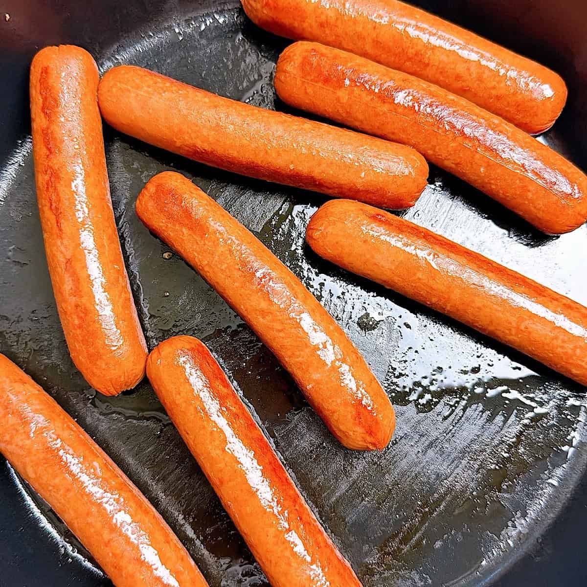 Cooked hot dogs in a skillet.