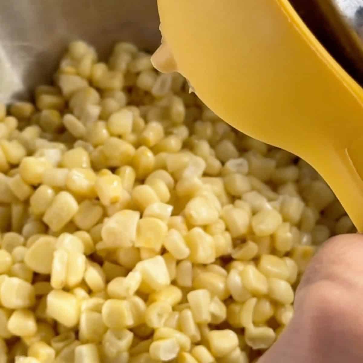 Adding lime juice with a lime squeezer to the corn.
