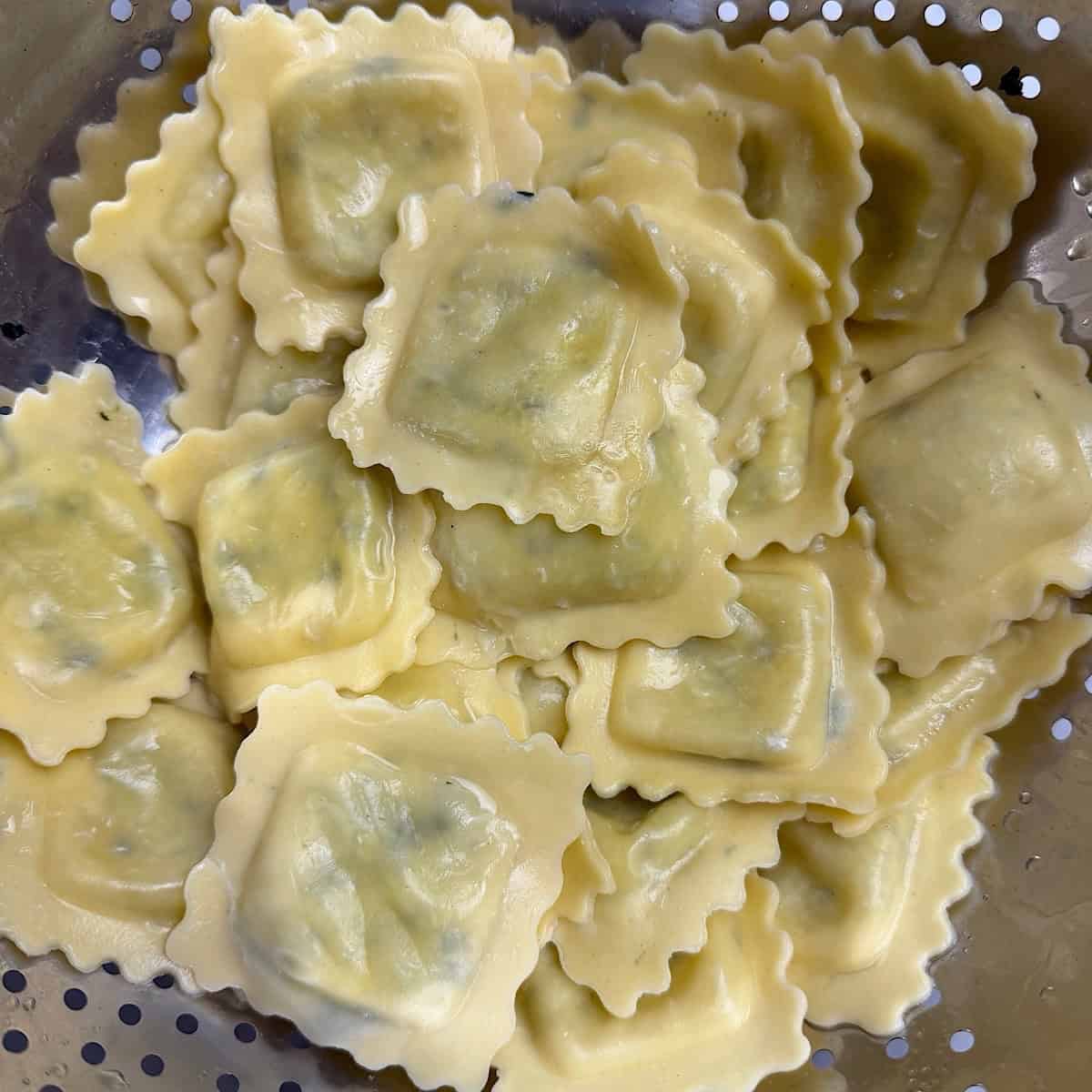 Spinach ravioli draining in a colander.
