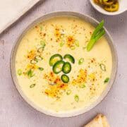 Creamy queso blanco dip in a bowl with paprika, green onion, and jalapeno garnish.