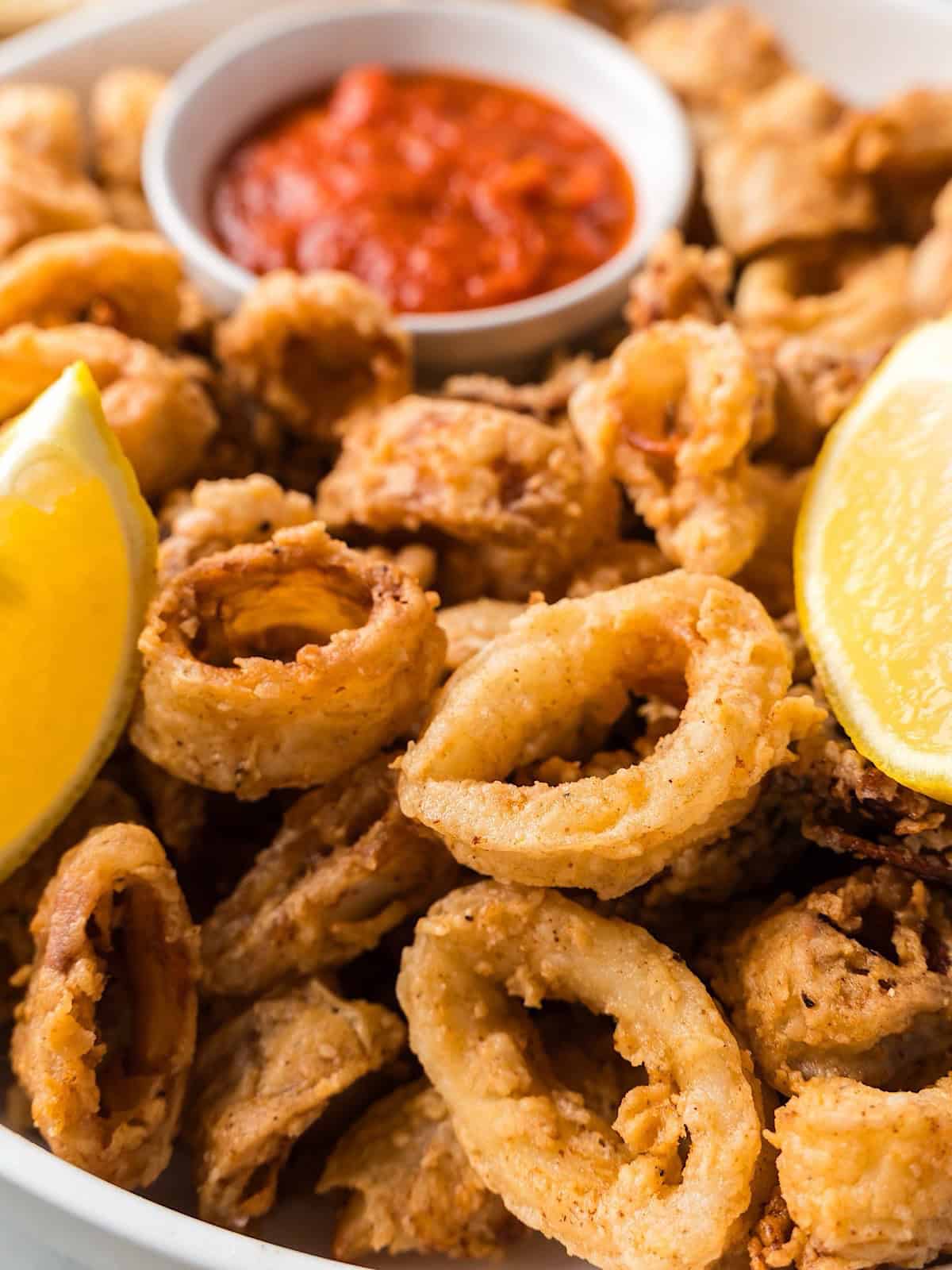 Fried calamari in white serving bowl with lemon and marinara.