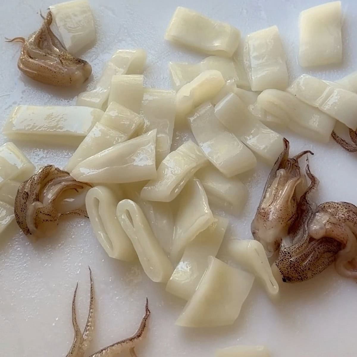 Slices squid and tentacles on a cutting board.