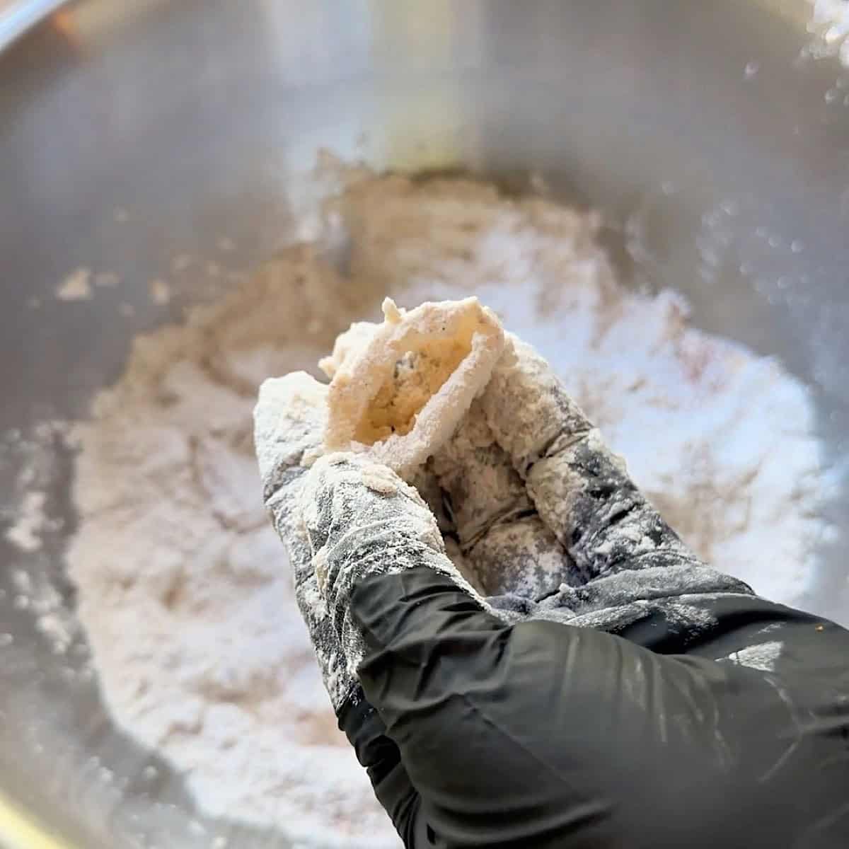 Holding a calamari ring that has been lightly coated with flour.