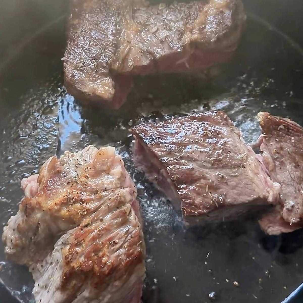 Seasoned and seared beef in a dutch oven browned.