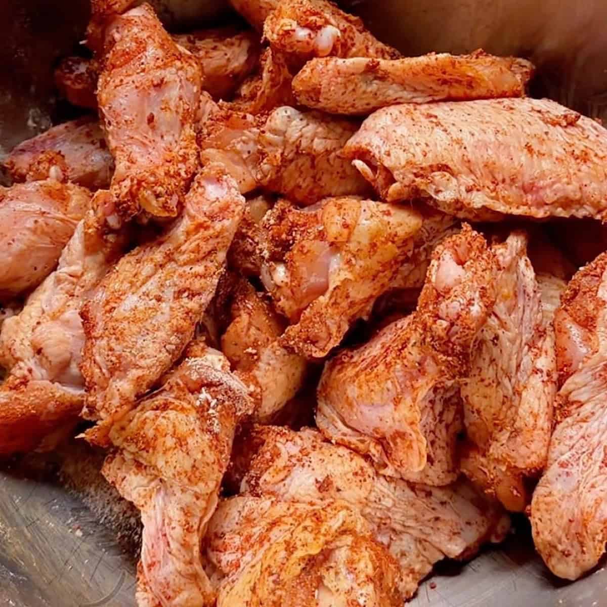Seasoned chicken wings in a mixing bowl.