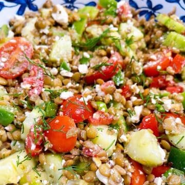 A greek lentil salad tossed in a decorative bowl to show dressing and herbs.