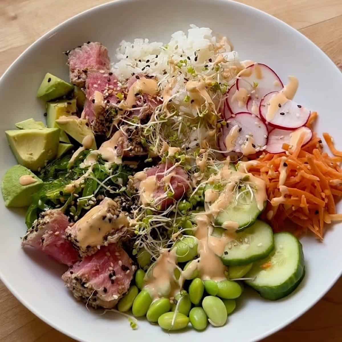 Seared ahi tuna, sprouts, and sriracha mayo sauce added to the bowl.