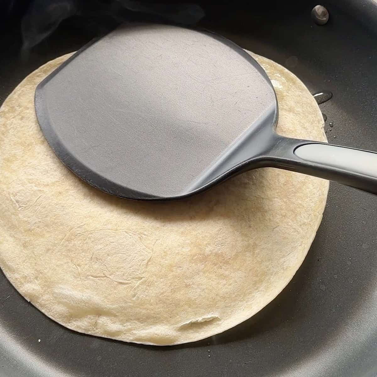 Smashing the taco beef side down with a spatula.