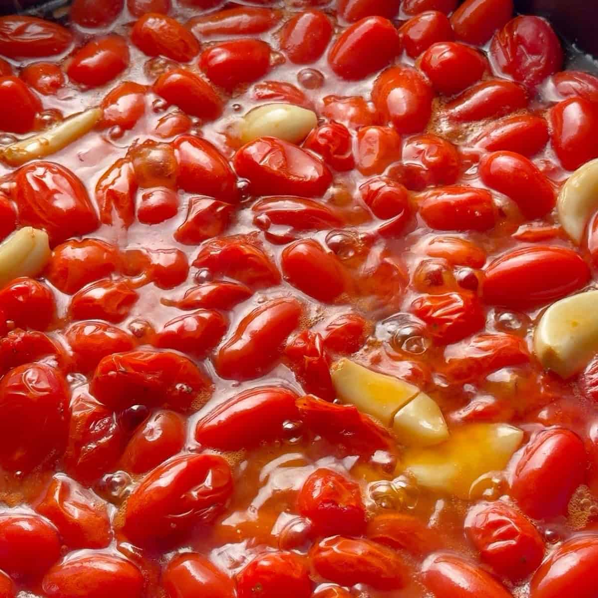 Tomatoes bubbling in oil looking wrinkled and collapsed.