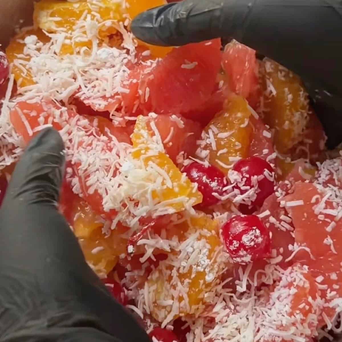 Gently tossing the ambrosia salad by hand to prepare for chill.