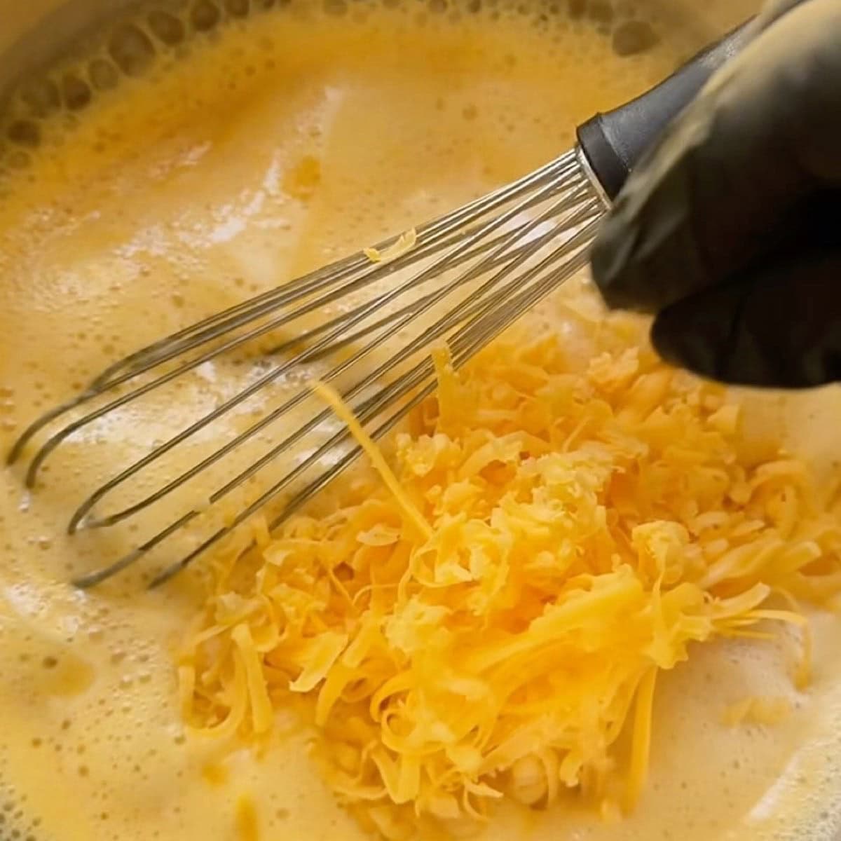 Adding cheddar one handful at a time while whisking.