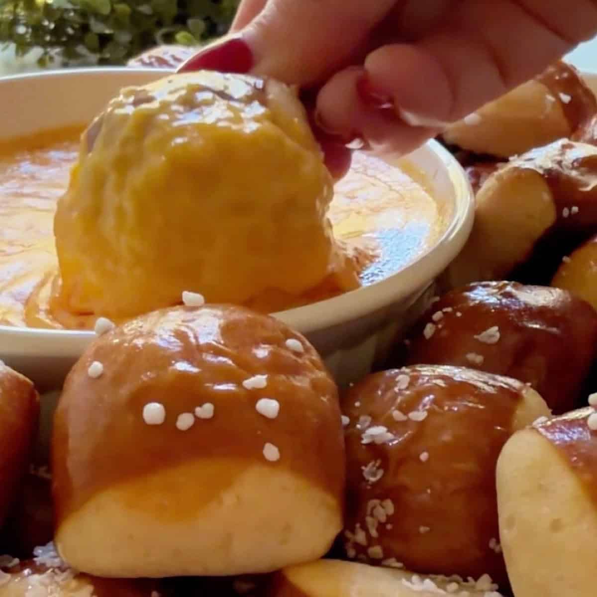 Dipping a pretzel in the beer cheese to show how it coats the pretzel.