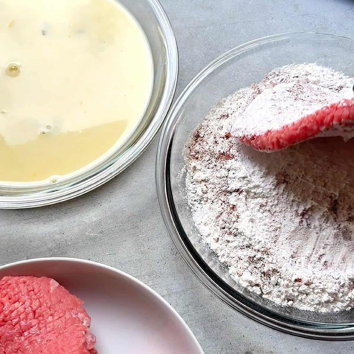 Dredging the cube steak in flour and seasoning.