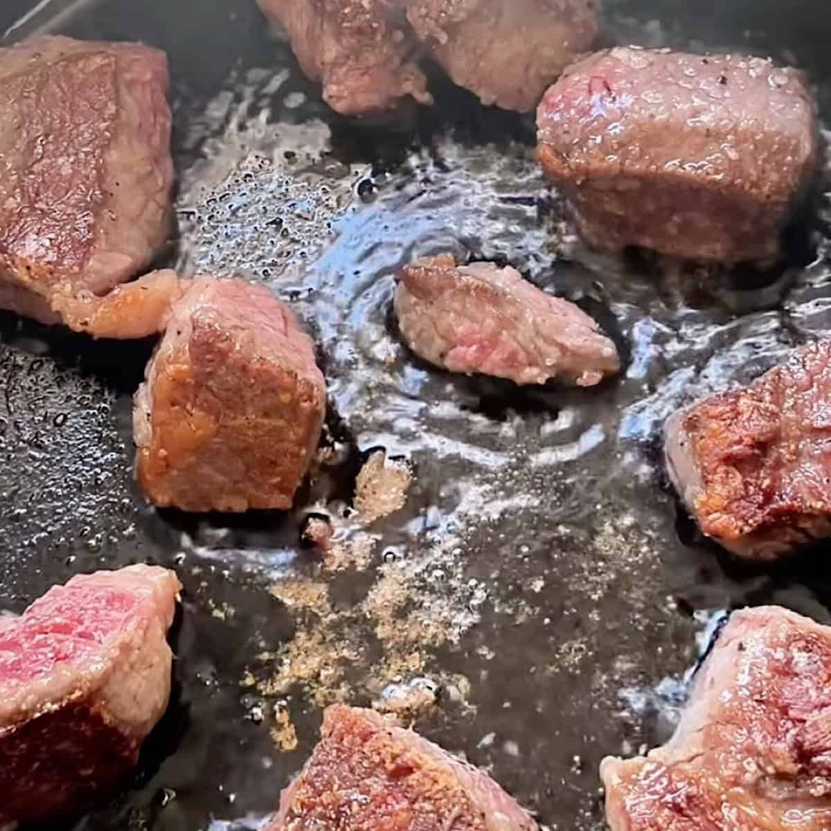 Searing the flour coated chuck roast until golden brown.