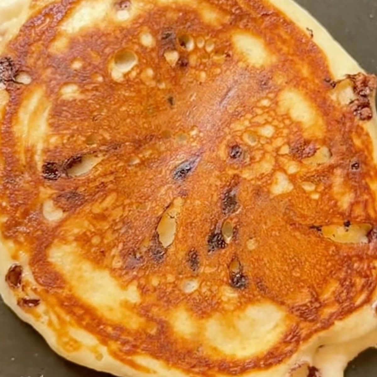 Cooked chocolate chip pancake in skillet to show proper browning.