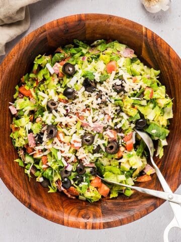 Chopped Italian Grinder Style Salad in a wooden bowl with serving utensil.