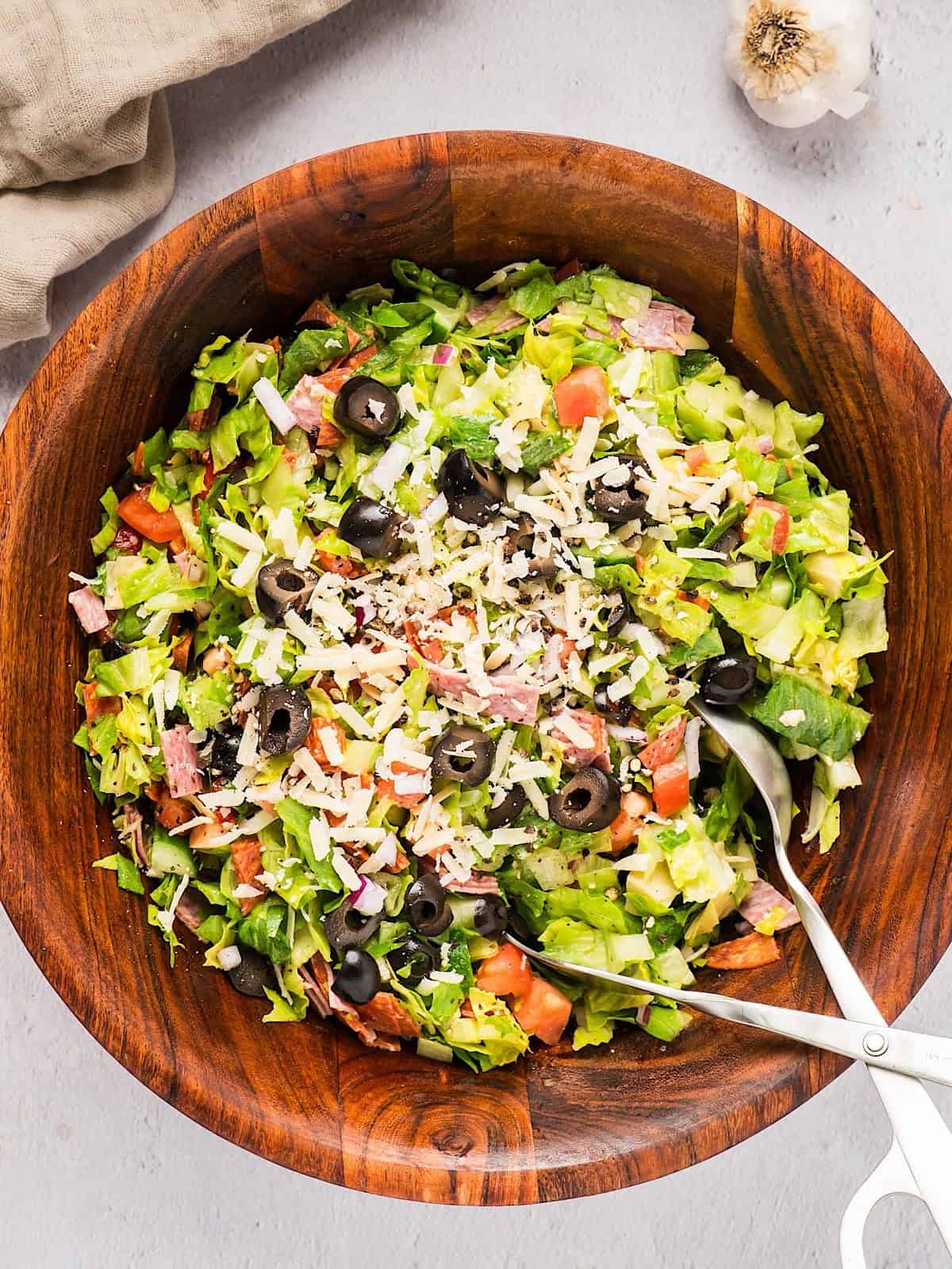 Chopped Italian Grinder Style Salad in a wooden bowl with serving utensil.