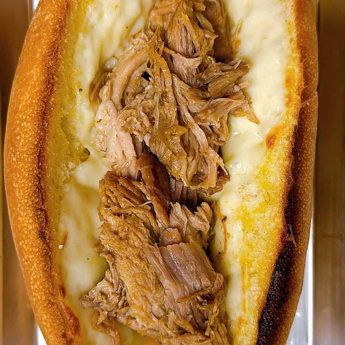 Toasted mojo pork sandwich assembled with melted cheese.