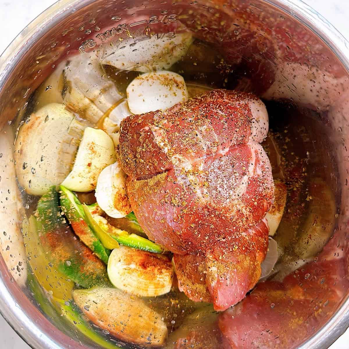 Seasoned pork shoulder on top of mojo marinade.