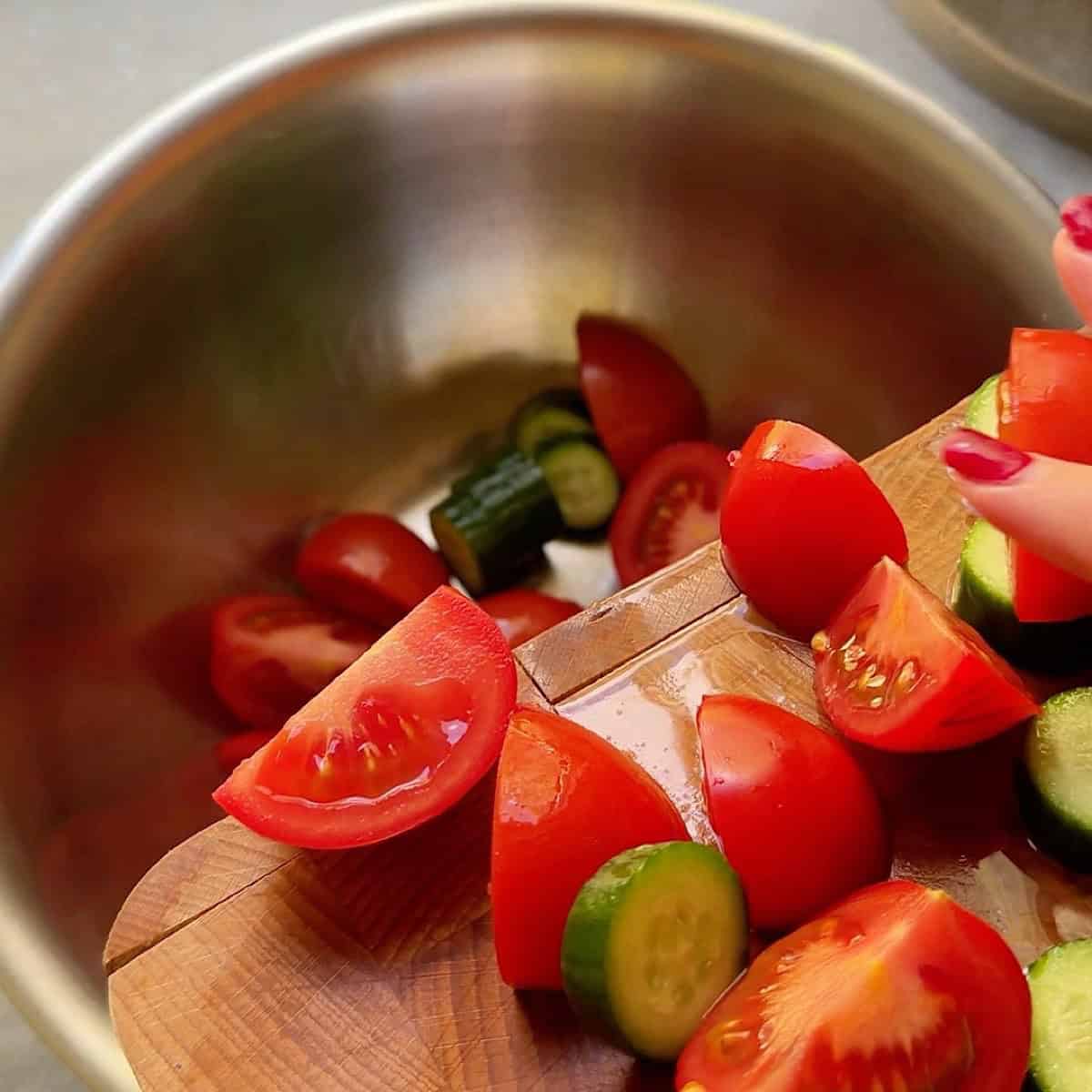 Sliding cut vegetables into a bowl from cutting board.