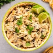 Southwest chicken salad in a Tex Mex style bowl next to cilantro, crackers, and wooden spoon.