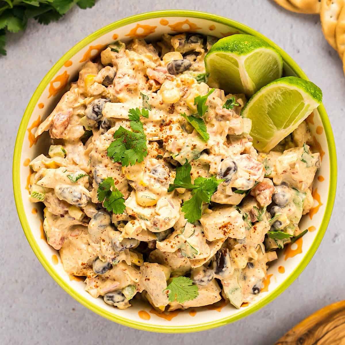 Southwest chicken salad in a Tex Mex style bowl next to cilantro, crackers, and wooden spoon.