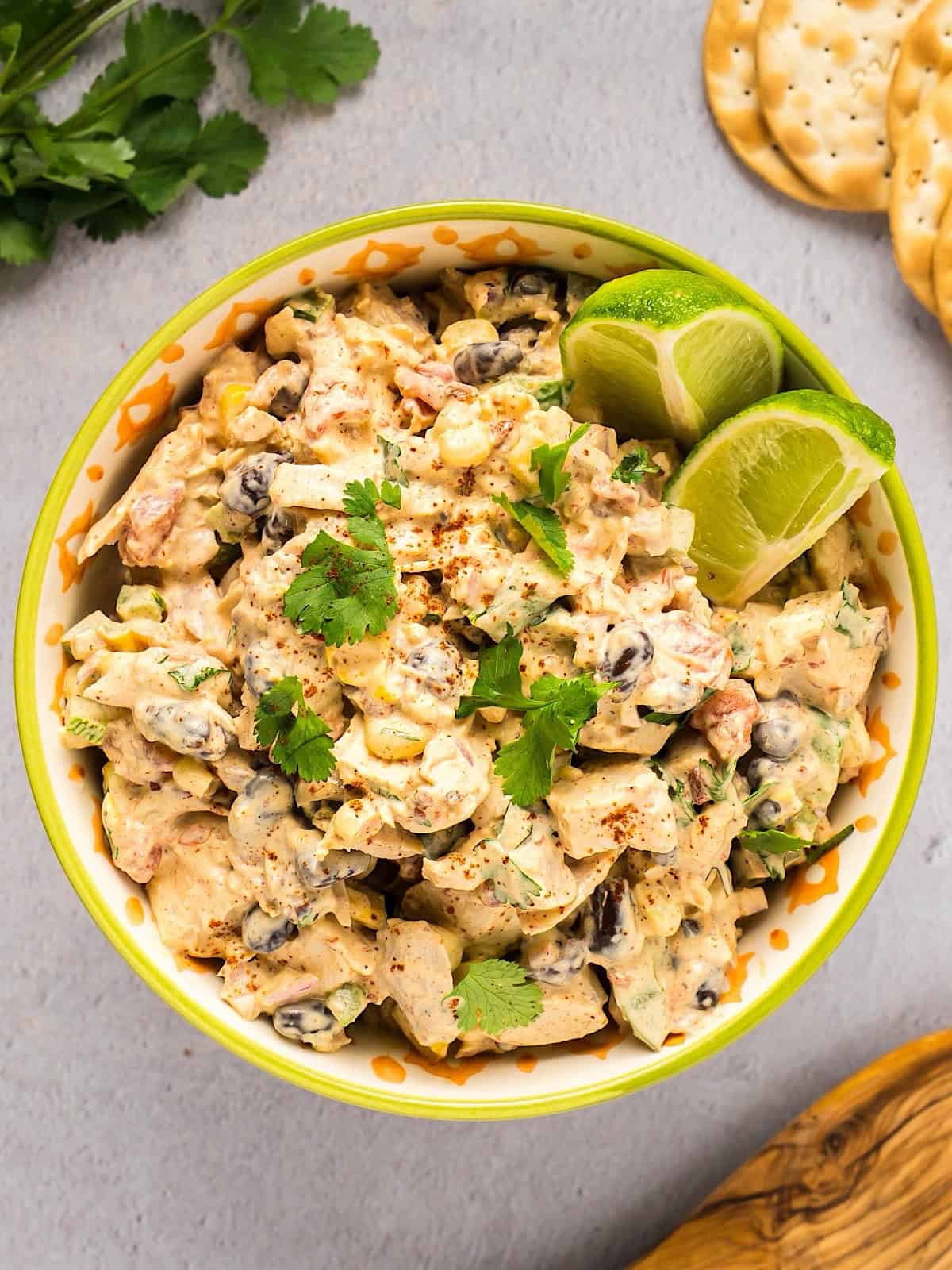 Southwest chicken salad in a Tex Mex style bowl next to cilantro, crackers, and wooden spoon.